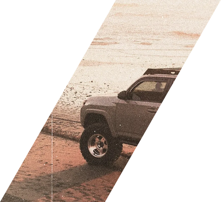 A four-wheel drive with a roof rack on wet sand